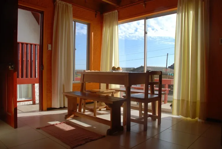 Comedor de madera junto a ventanales dentro de la cabaña
